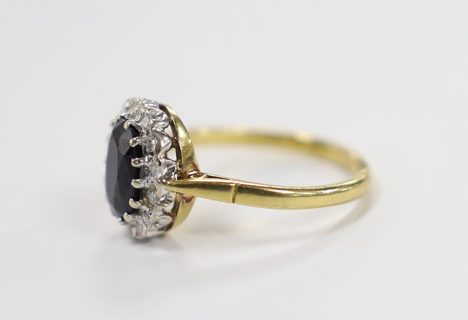 A modern 18ct gold, sapphire and diamond set oval cluster ring, size Q, gross weight 4.9 grams.